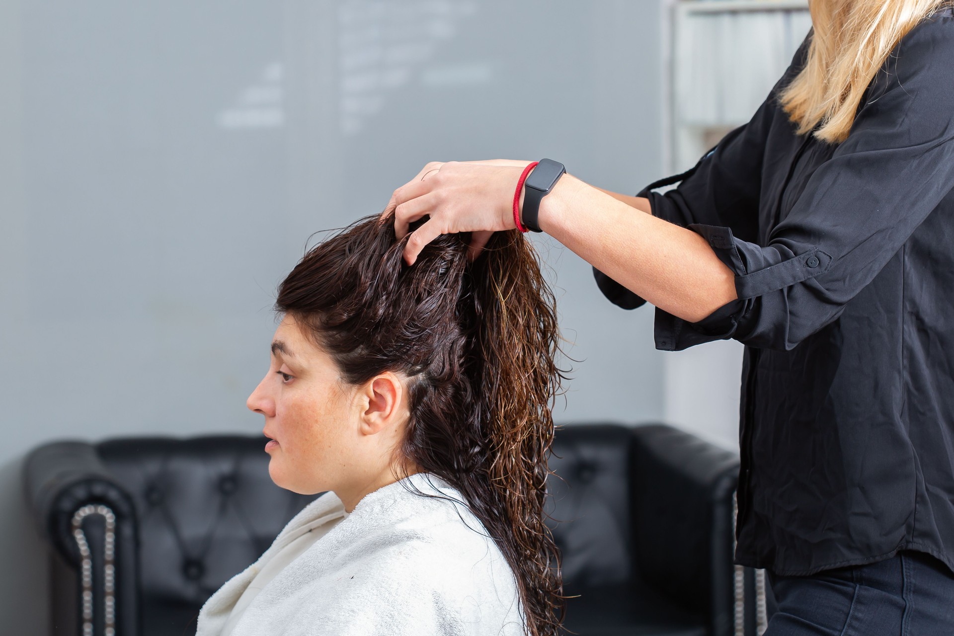 Woman receiving a hair treatment from stylist in a salon, focused on hair care and styling services.