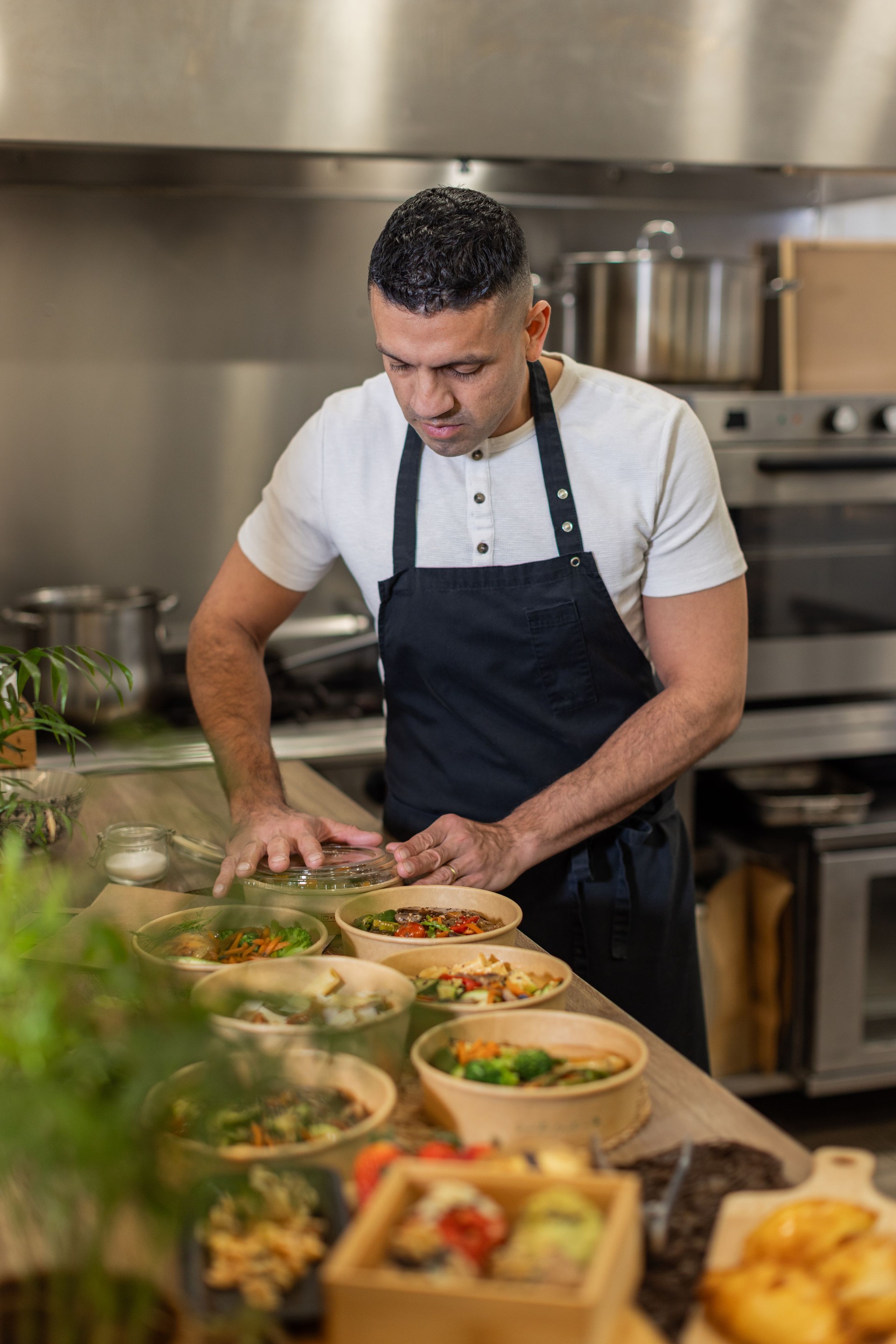 Chef preparing healthy meal options in a restaurant kitchen, focusing on fresh ingredients in bowls, emphasizing local food preparation and culinary expertise.